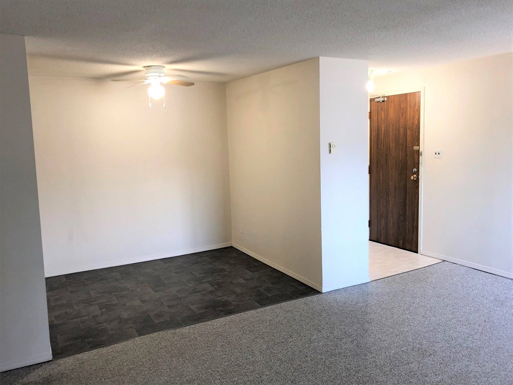 a empty living room with white walls and a wooden door