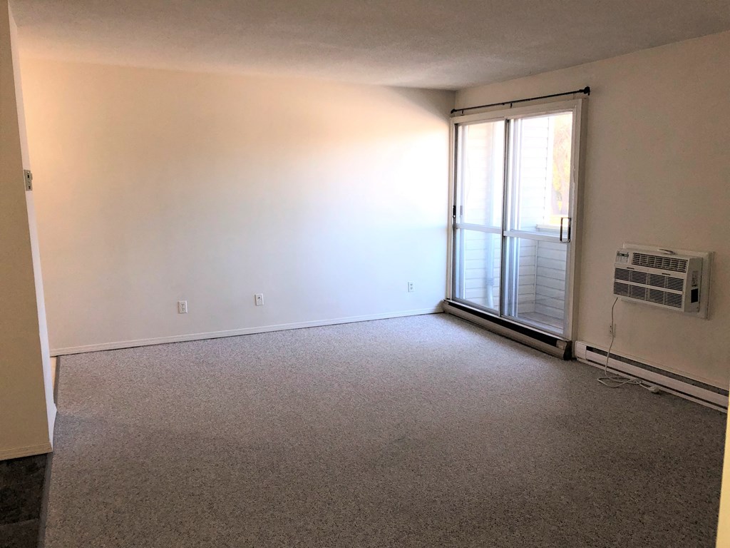 an empty living room with a heater and a sliding glass door