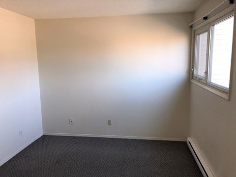 an empty room with a window and a carpet