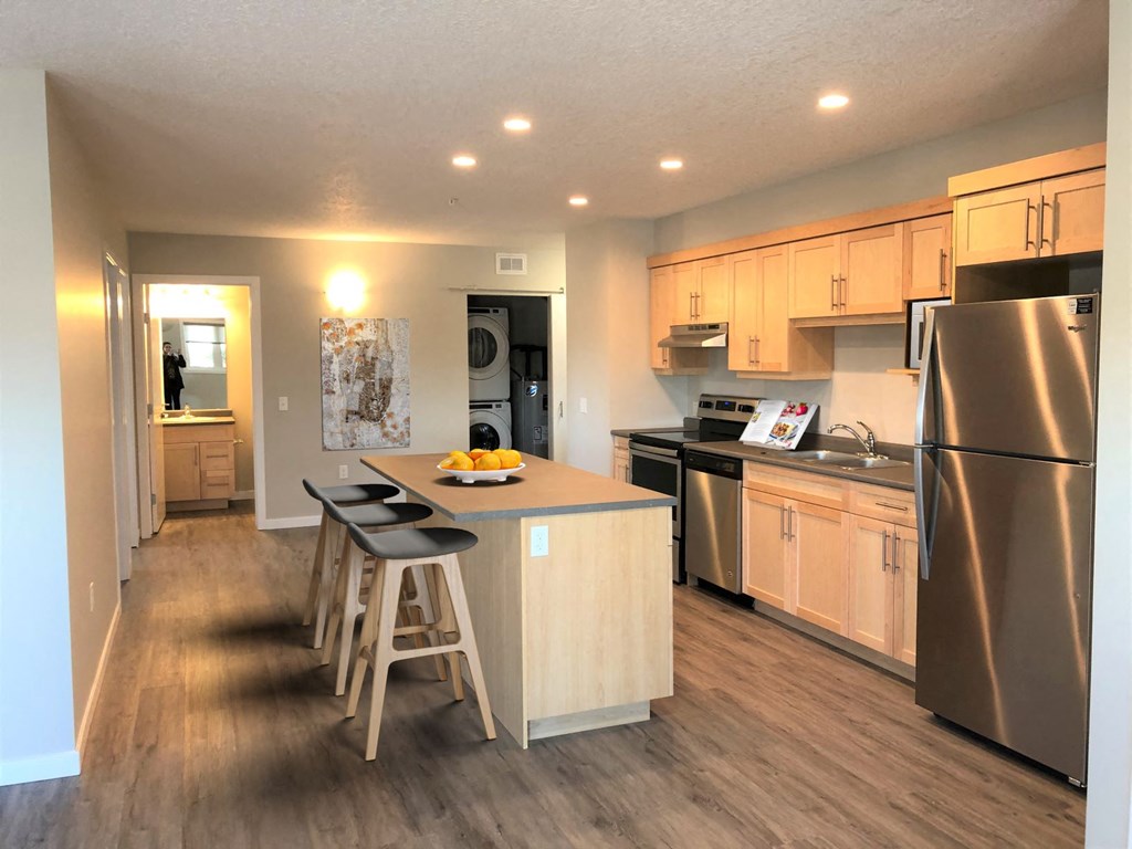 a kitchen with stainless steel appliances and a bar with three stools