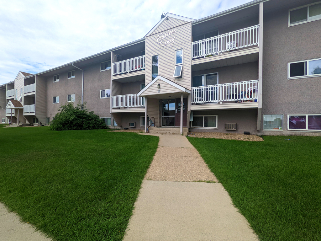 an exterior view of an apartment building with a sidewalk and lawn