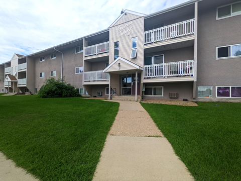 an exterior view of an apartment building with a sidewalk and lawn
