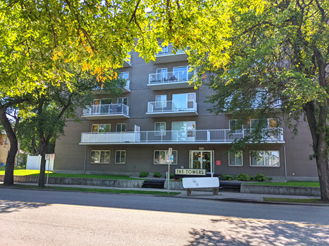 an apartment building on the corner of a street with trees