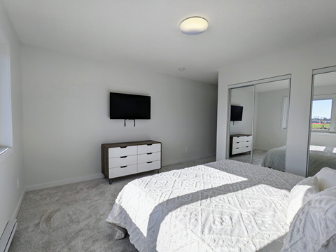 a bedroom with a bed and a tv on the wall