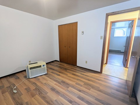 an empty living room with wood flooring and a heater
