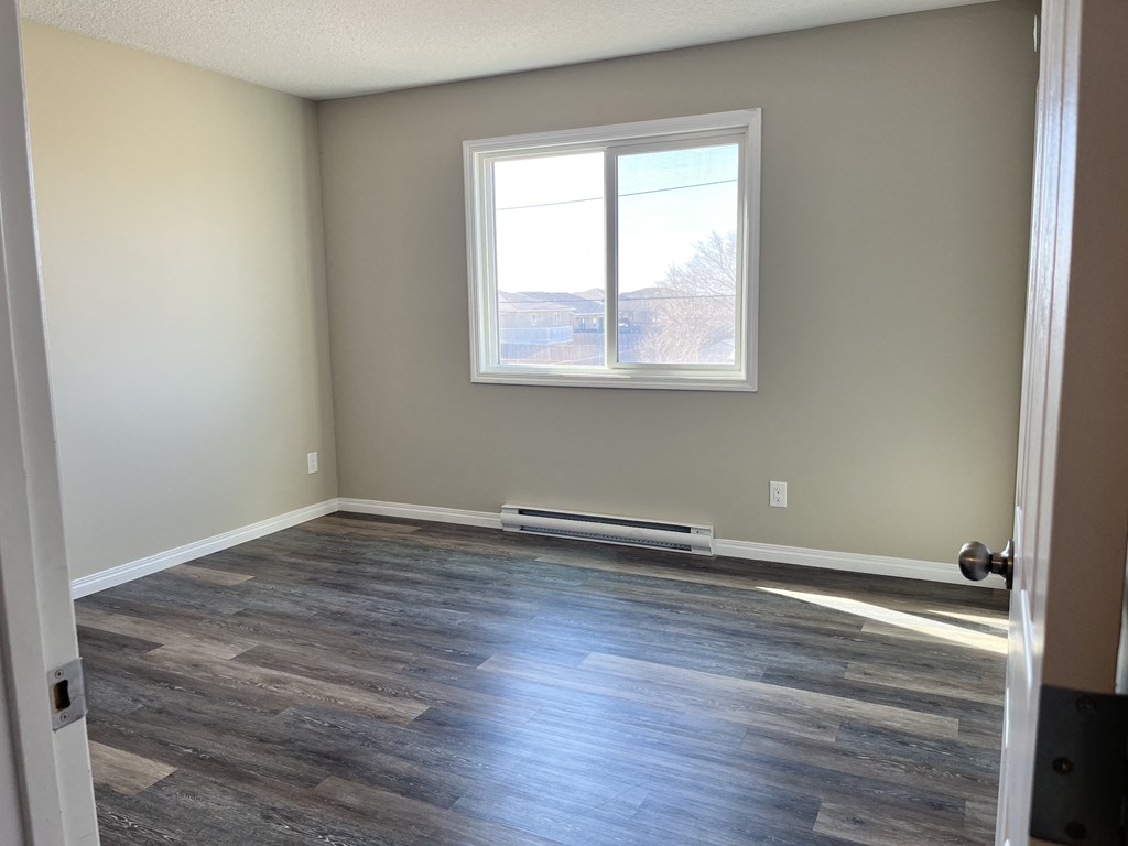an empty room with wooden floors and a window