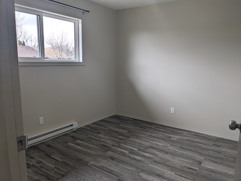 an empty room with wooden floors and a window