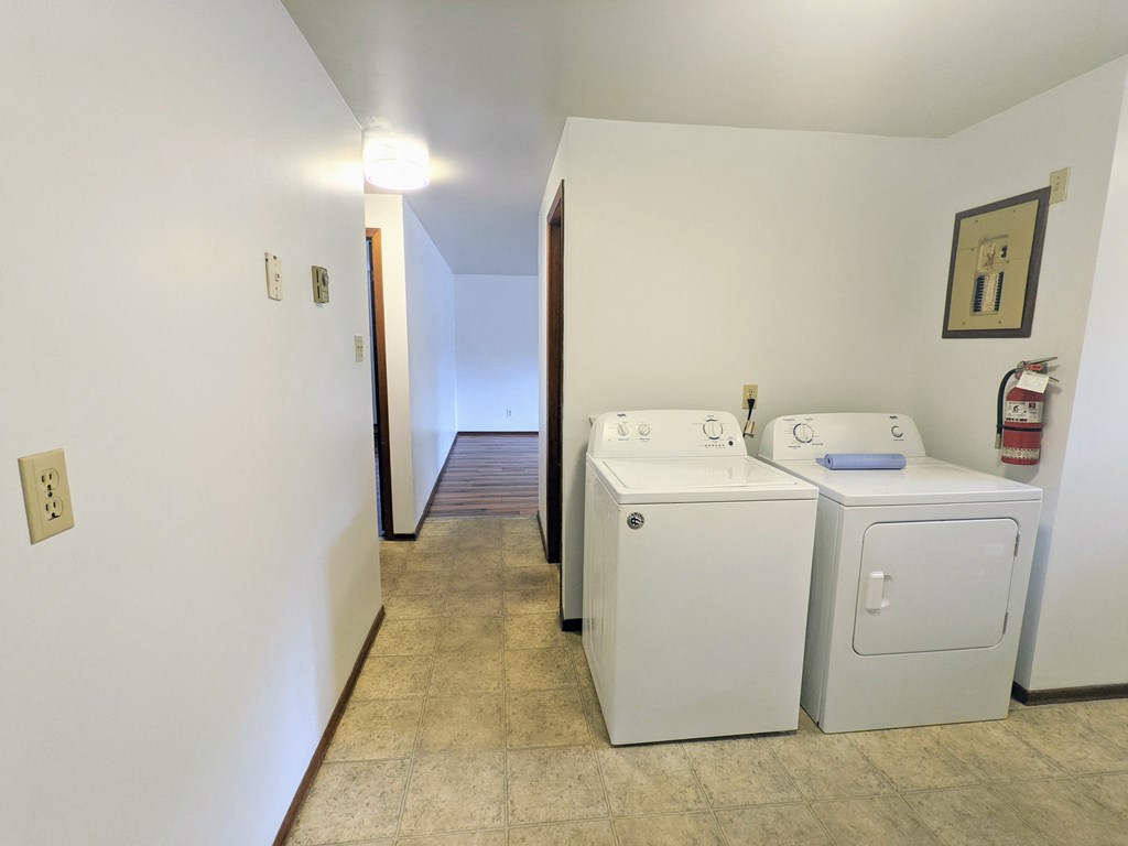 a washer and dryer in a laundry room with a hall to a door