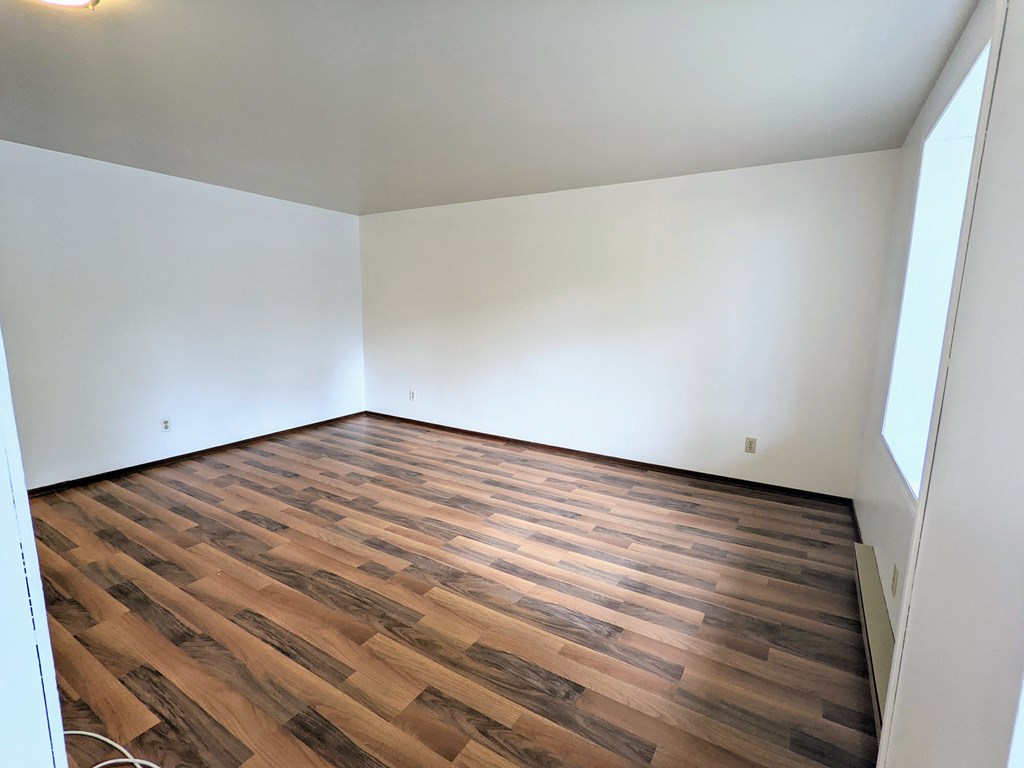 an empty room with wood flooring and white walls