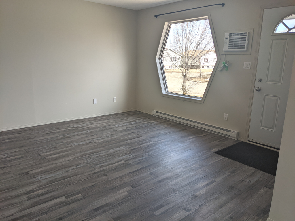 an empty living room with wood floors and a window