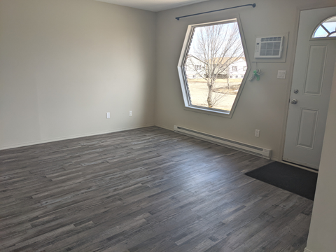 an empty living room with wood floors and a window
