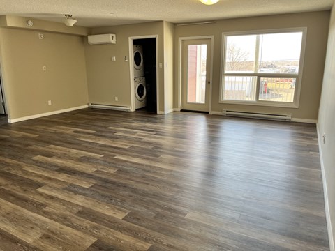 an empty living room with a hard wood floor and a window