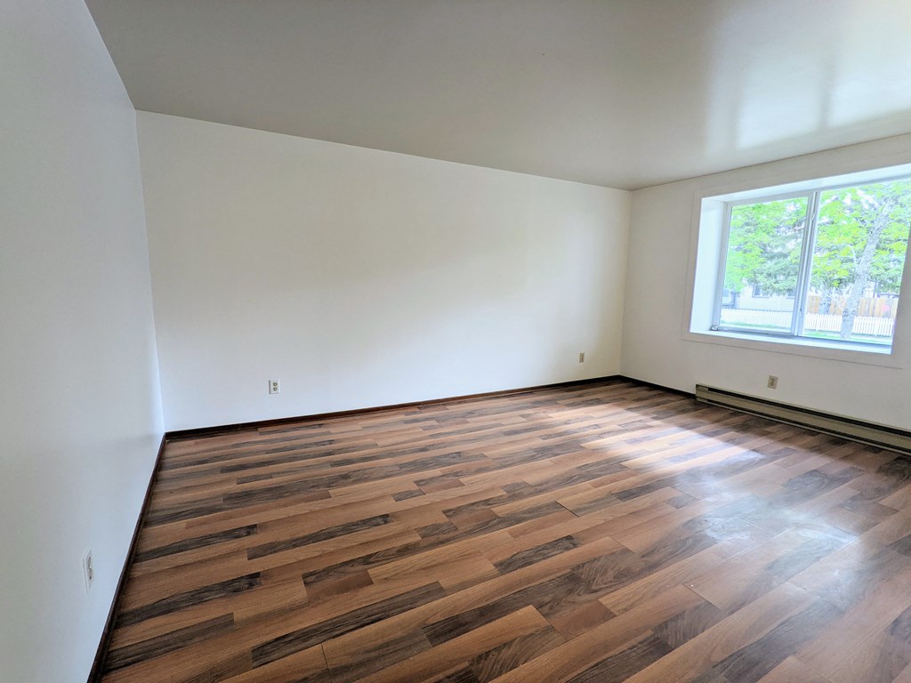 an empty room with wooden floors and a window