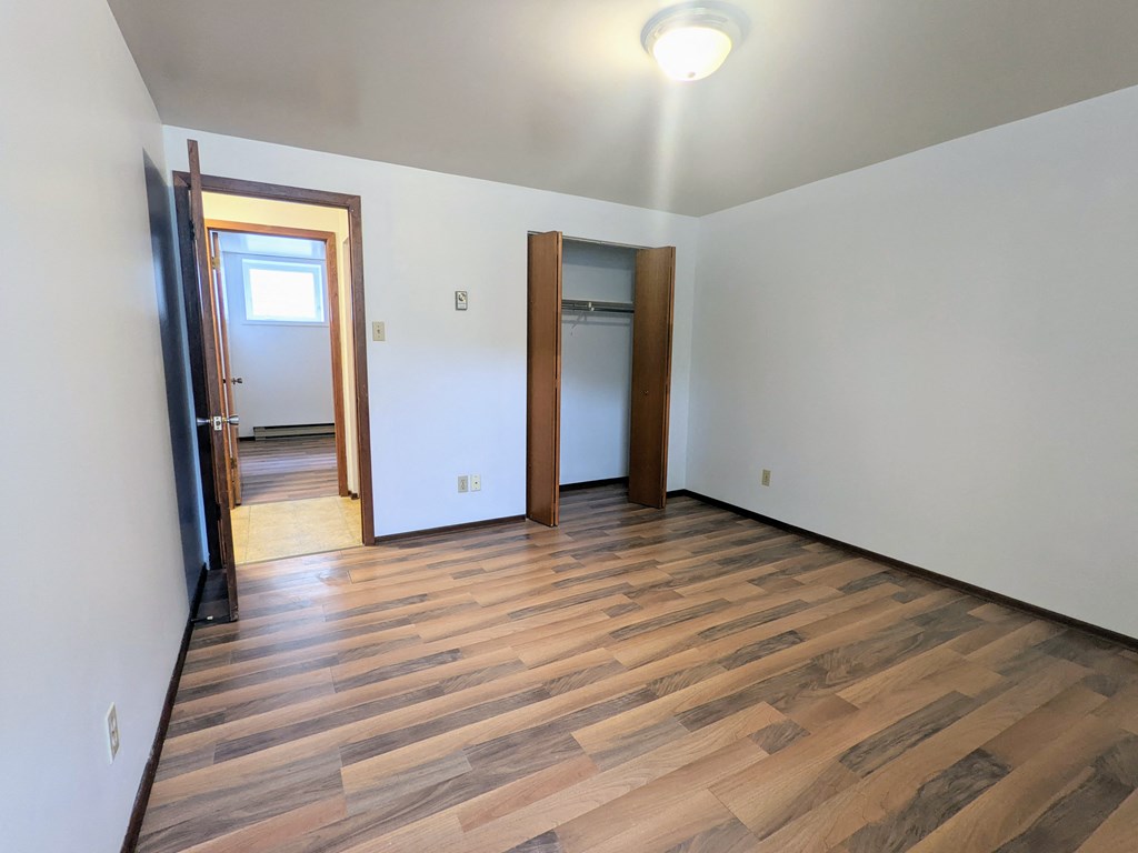 a empty living room with wood flooring and a door to a closet