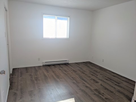an empty room with wooden floors and a window