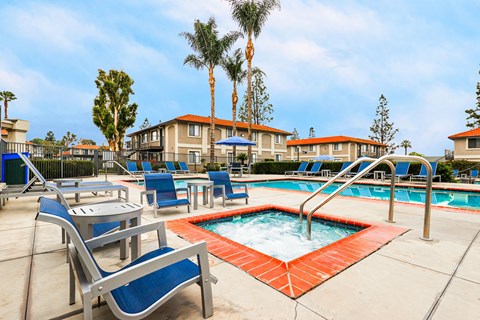A pool area with a hot tub and lounge chairs.