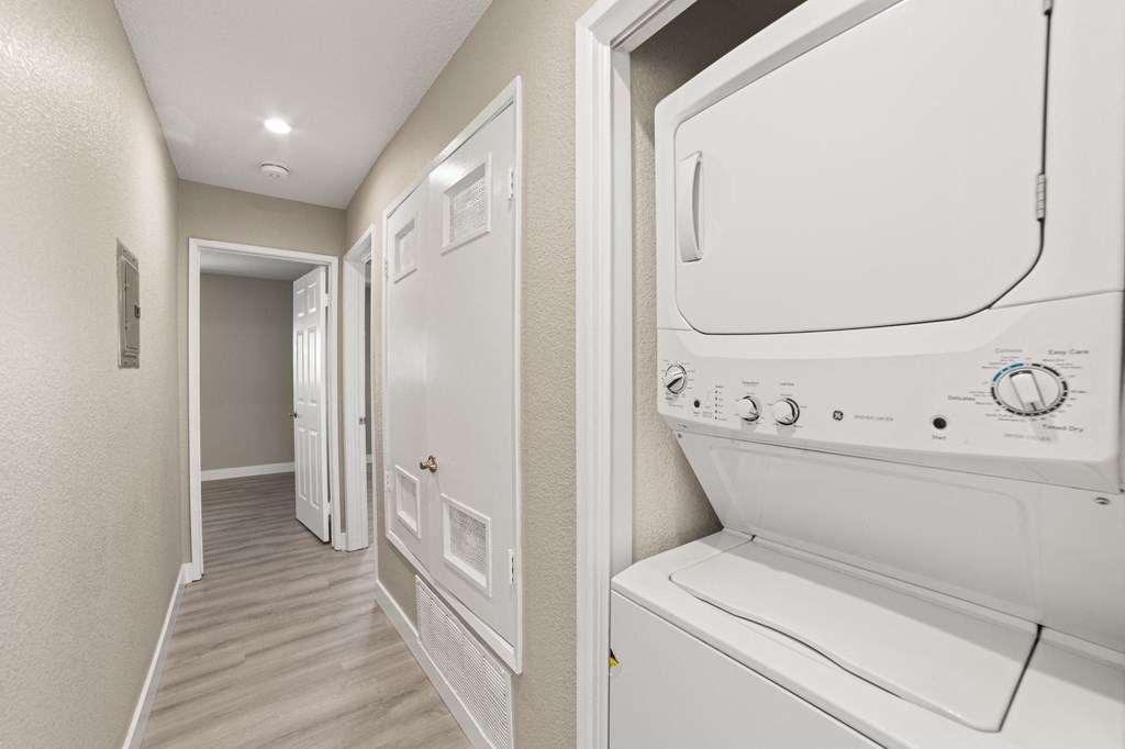 A white dryer is sitting in a narrow hallway.