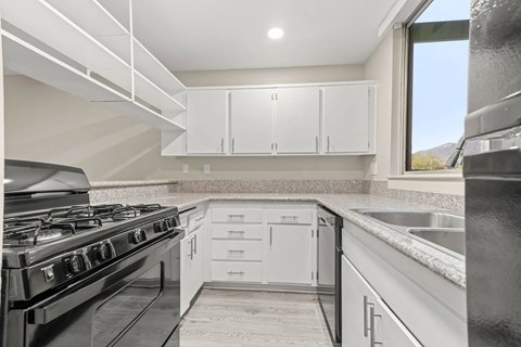 a kitchen with white cabinets and a stove and a sink