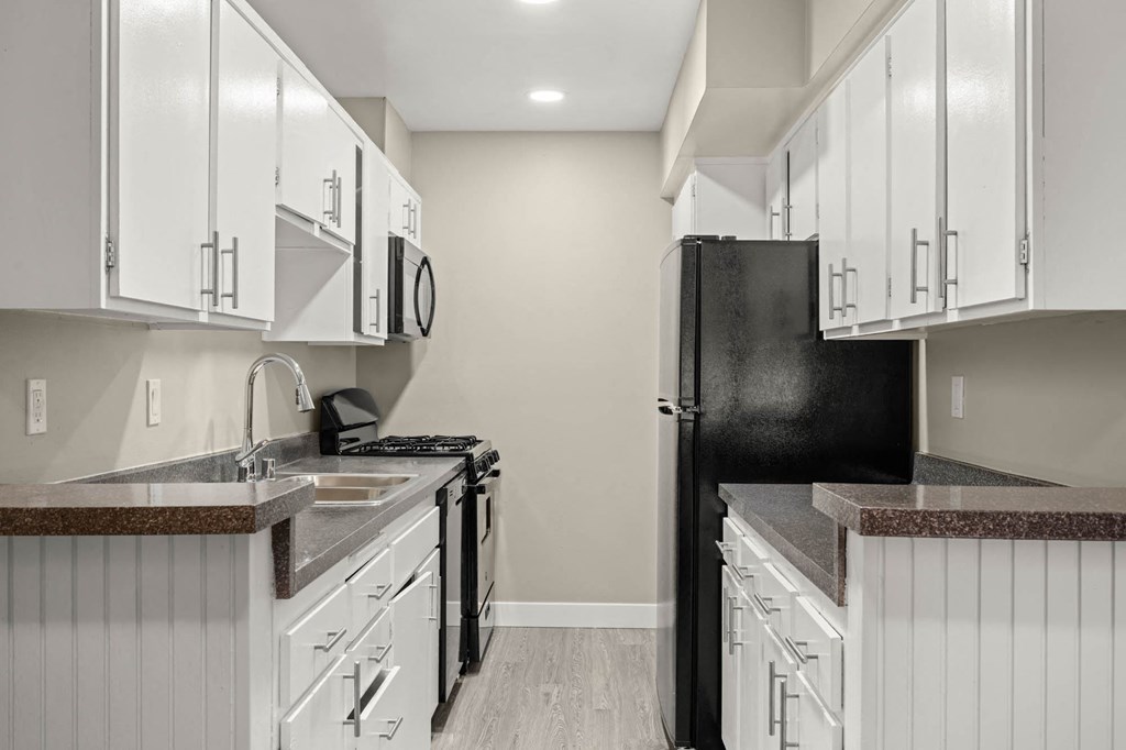 a kitchen with white cabinets and a black refrigerator