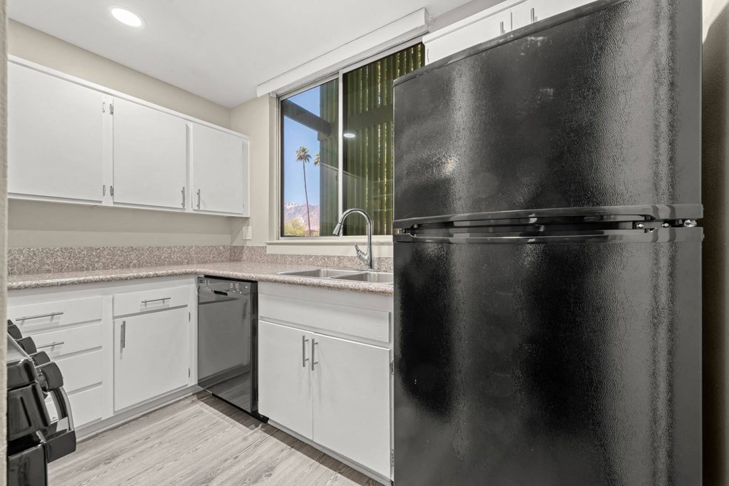a kitchen with white cabinets and a black refrigerator