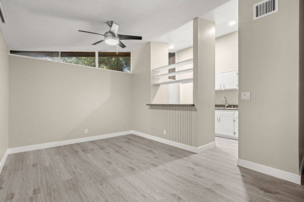 a bedroom with a ceiling fan and a kitchen in the background