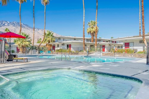 a swimming pool with palm trees and a building in the background