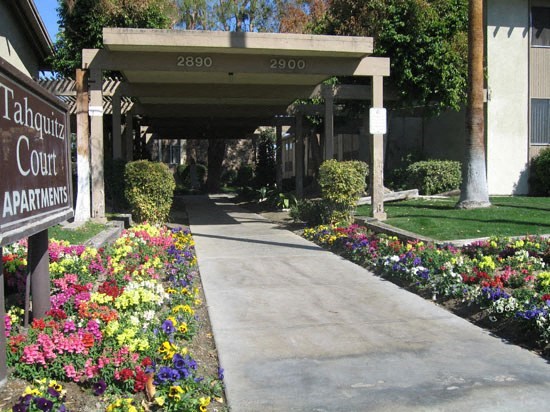 a sidewalk in front of a building with flowers and a sign