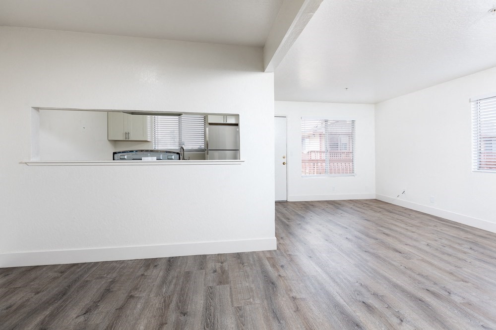 an empty living room with white walls and wood flooring