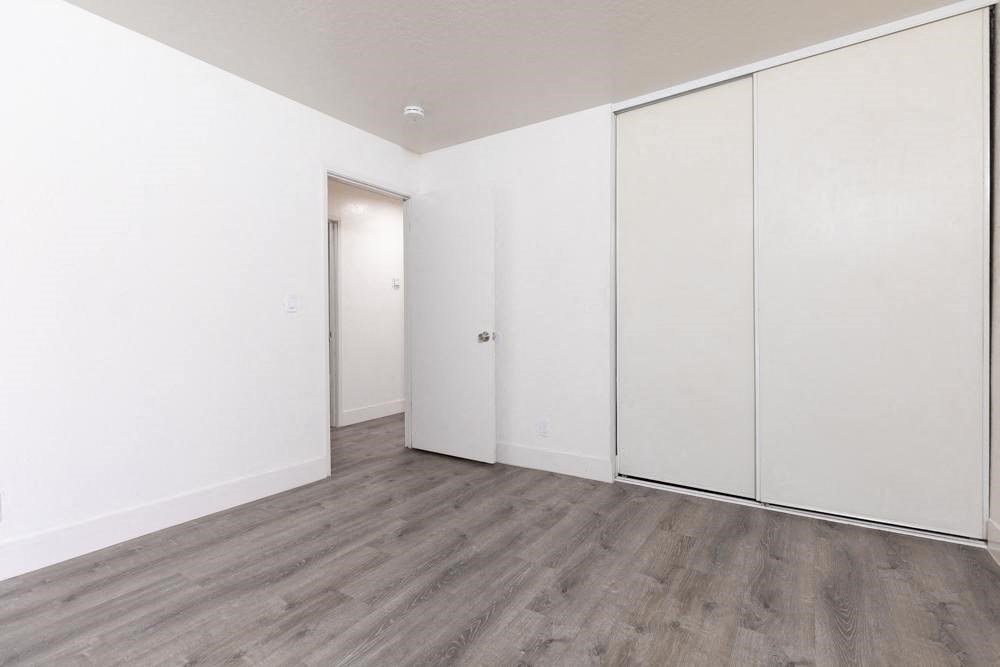 an empty bedroom with white walls and wood floors