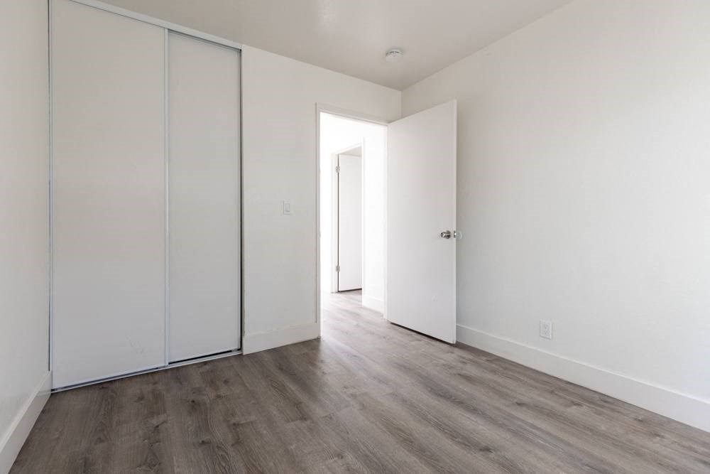 an empty bedroom with white walls and wood floors