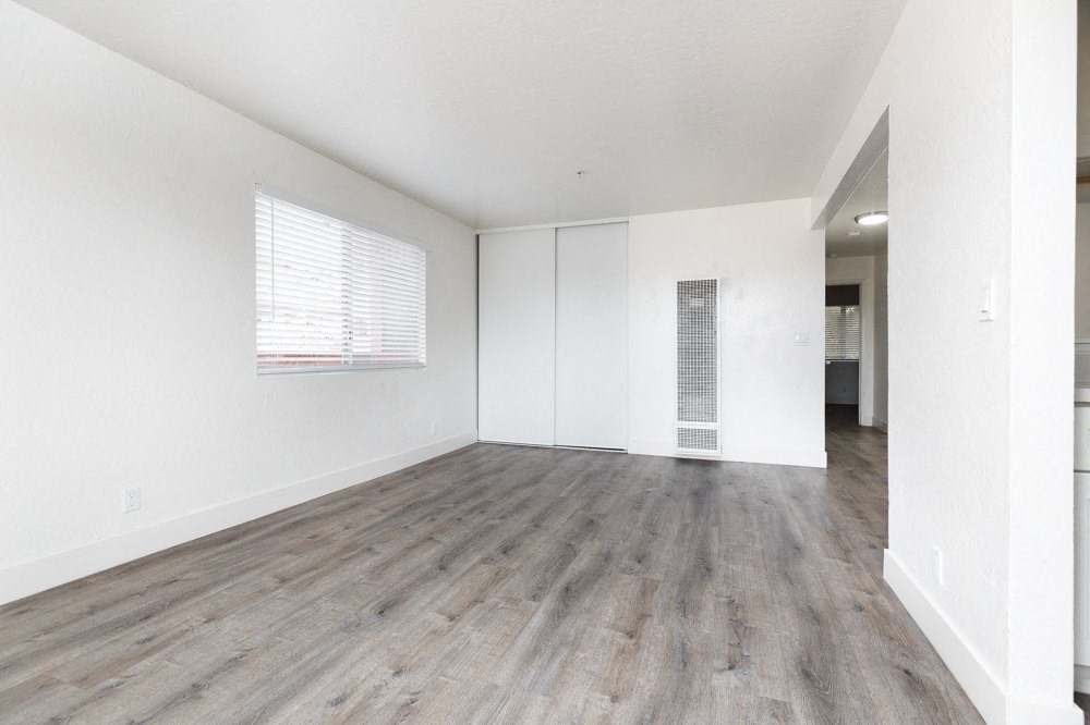 an empty living room with white walls and wood floors