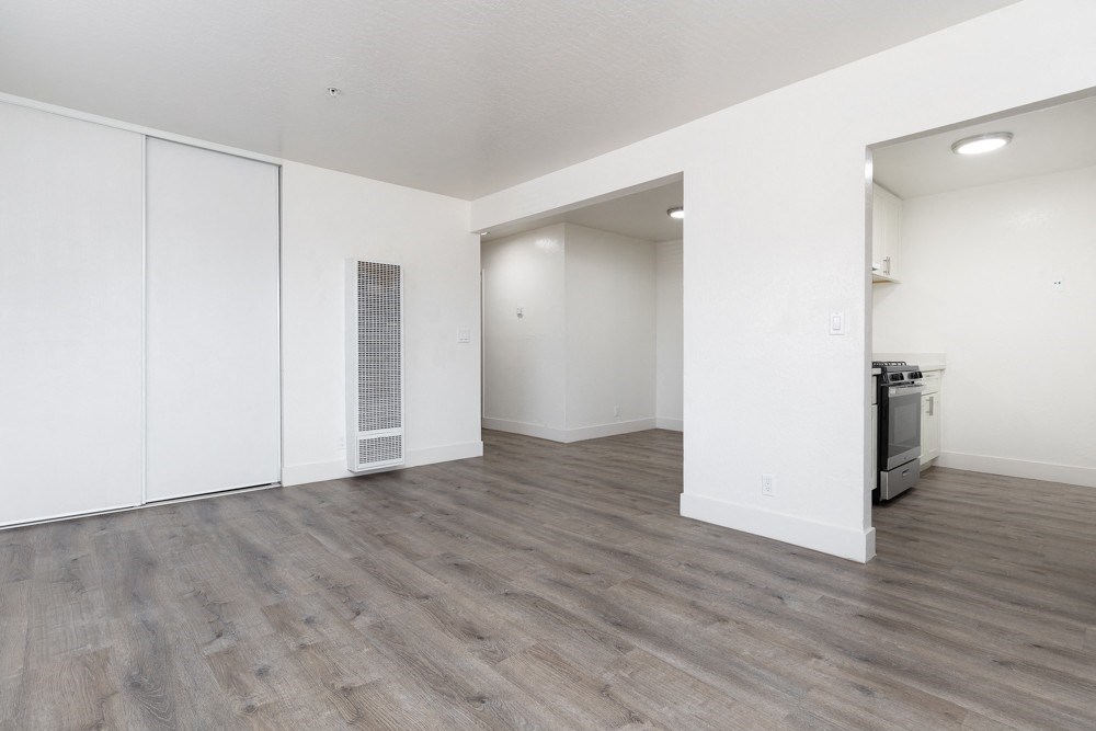 an empty living room with white walls and wood flooring