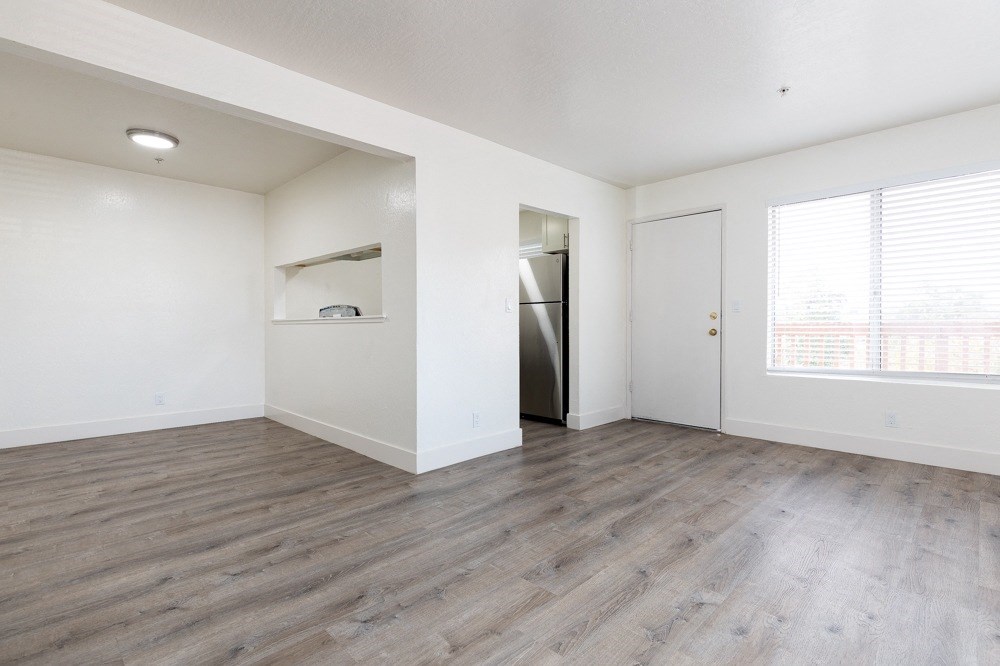 an empty living room with white walls and wood flooring
