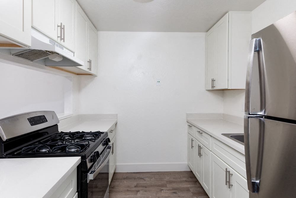 an empty kitchen with white cabinets and stainless steel appliances