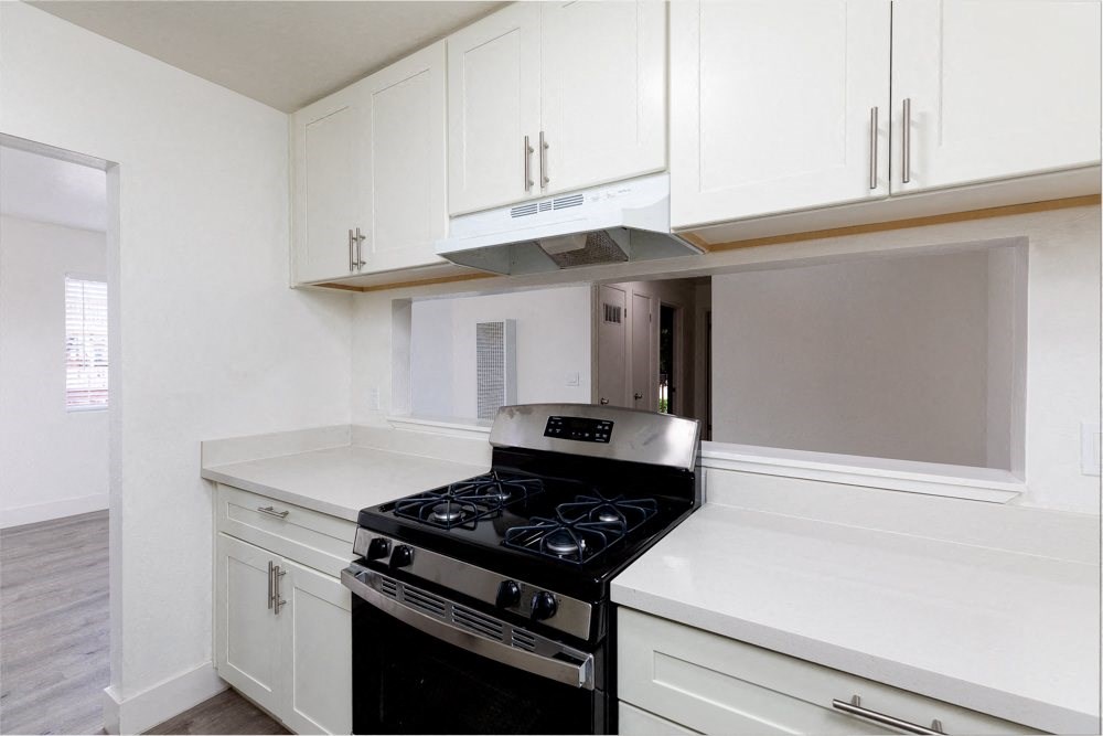 an empty kitchen with white cabinets and a black stove