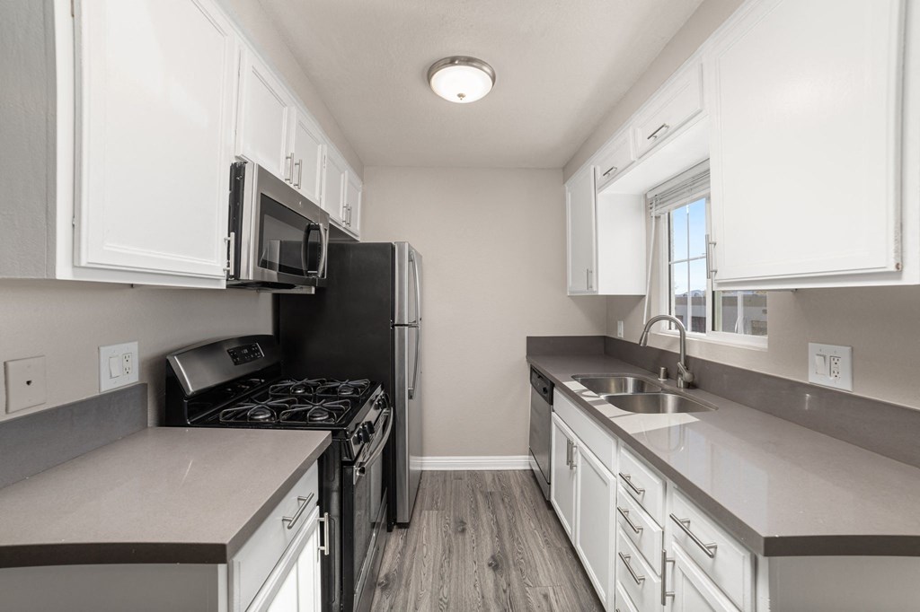 A kitchen with white cabinets and a black refrigerator.
