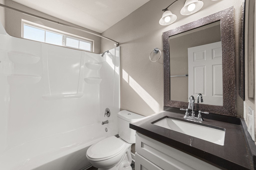 A white toilet sits in a bathroom next to a white bathtub.