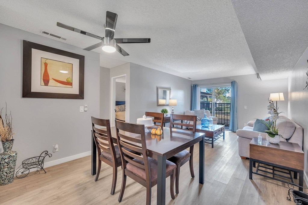a living room and dining room with a table and a ceiling fan
