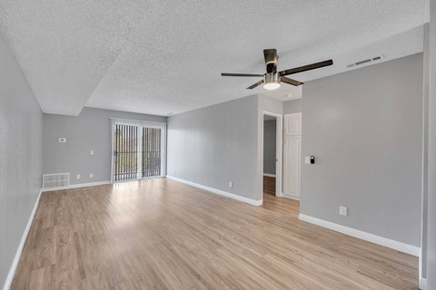 an empty living room with hardwood floors and a ceiling fan