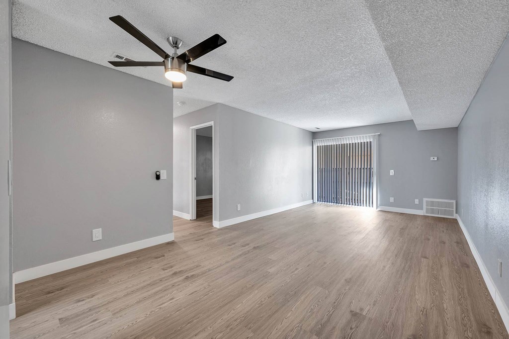 the living room and dining room of an empty house with a ceiling fan