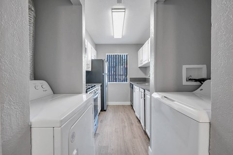 a white kitchen with white appliances and a wood floor