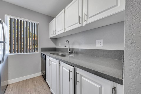 a kitchen with white cabinets and a sink and a window
