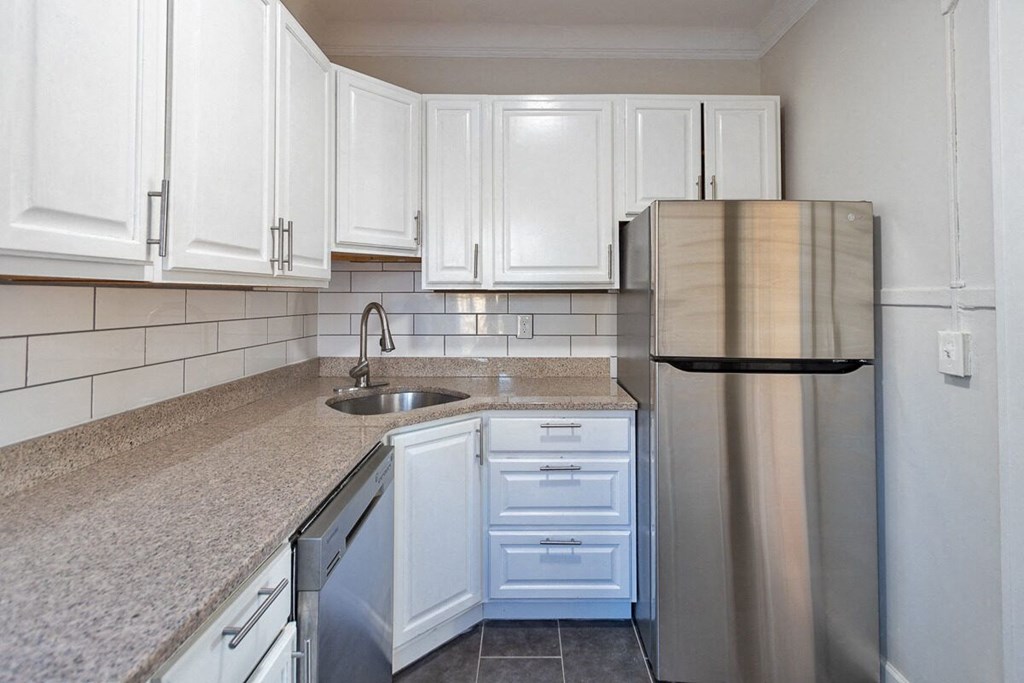 a kitchen with white cabinets and a stainless steel refrigerator