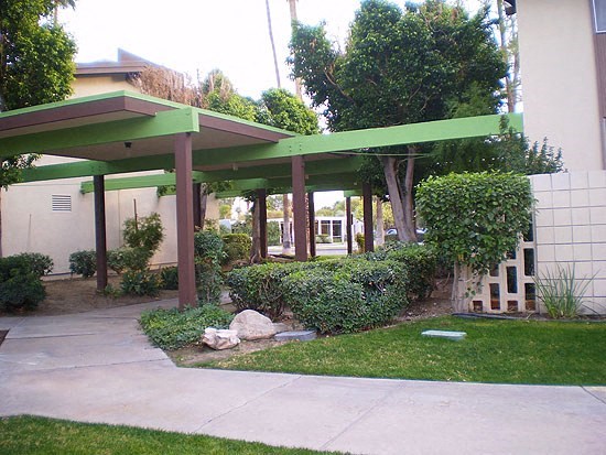 a patio with a green roof in a yard