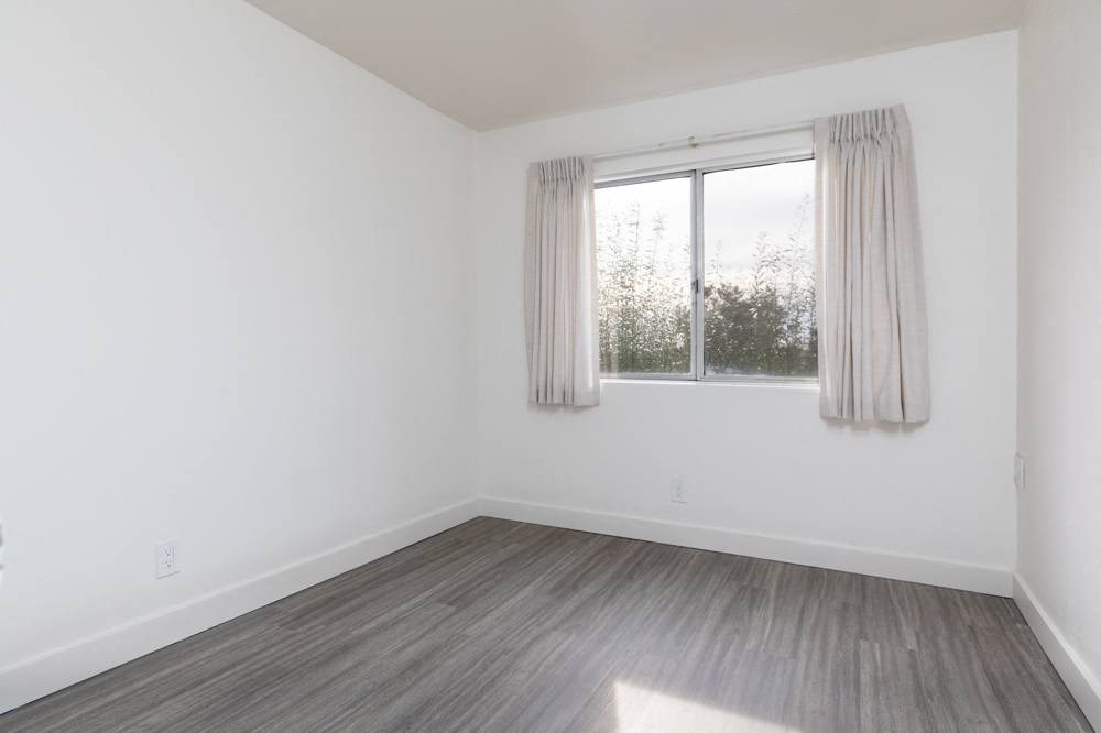an empty room with a window and wood floors