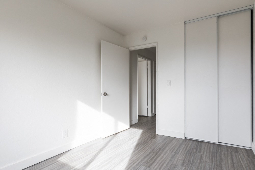 an empty room with white walls and wood floors
