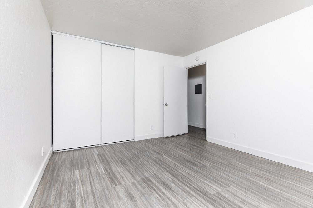 an empty room with white walls and wood floors