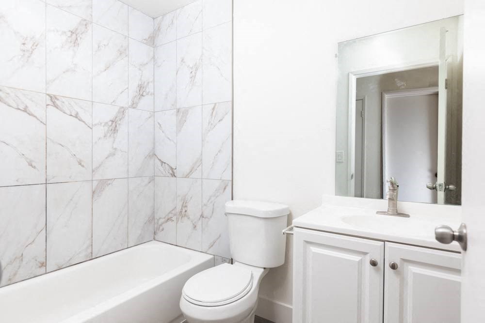 a white bathroom with a tub toilet and sink