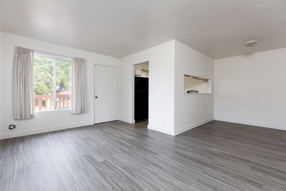 an empty living room with white walls and a window