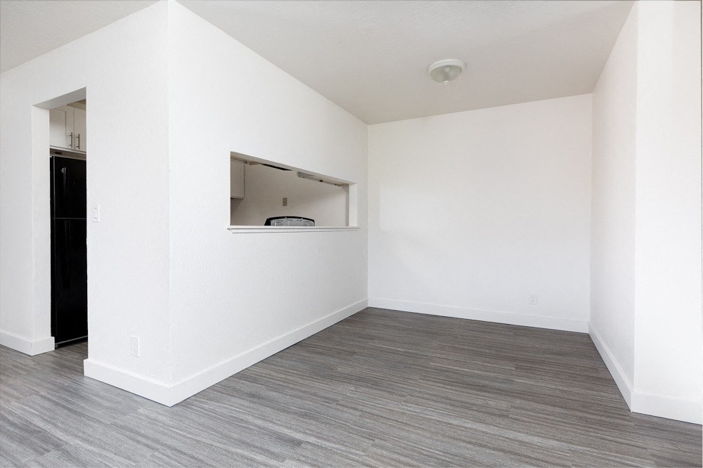 an empty living room with white walls and wood flooring